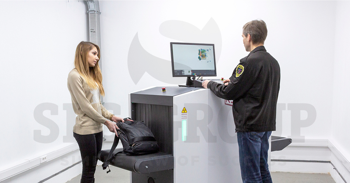 Сотрудник проверяет ручную кладь девушки с помощью рентгенотелевизионной установки